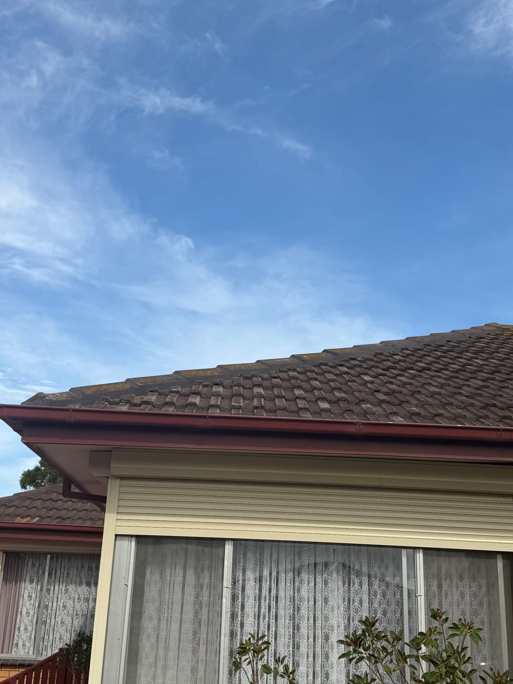 Charcoal tile roof under a bright blue Melbourne sky
