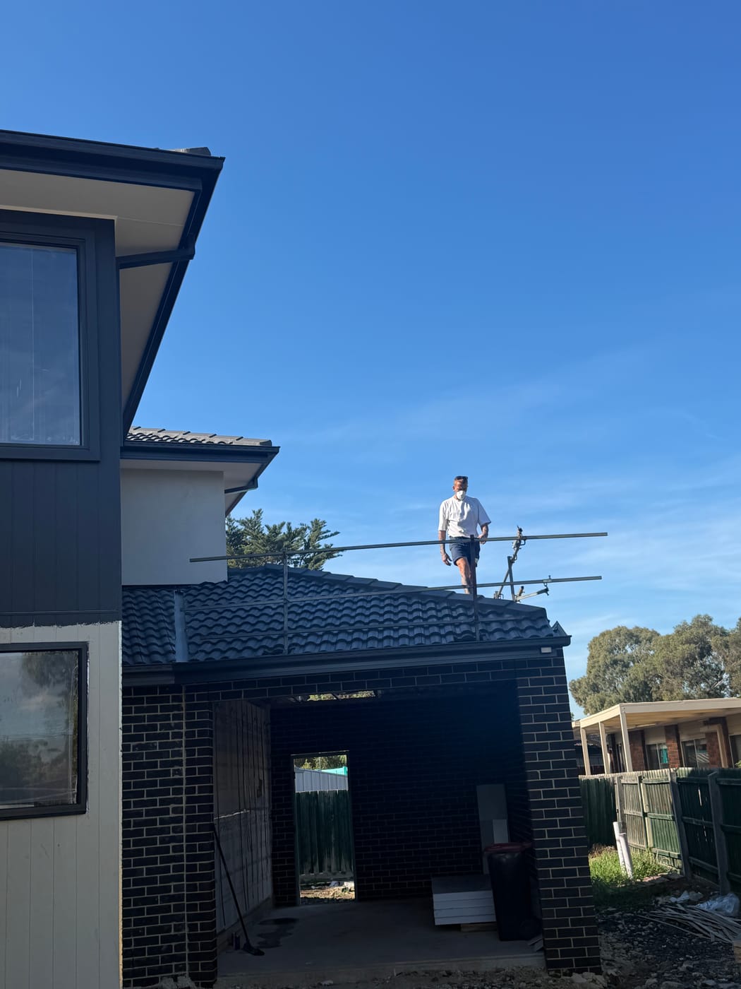 Wolfeden roofer working on a tile roof at golden hour above the Melbourne suburbs